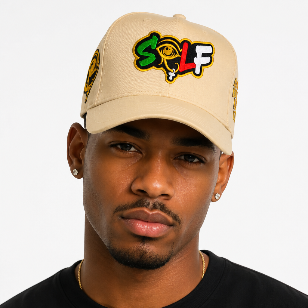 A man wearing a beige baseball cap with a colorful embroidered 'SOLF' logo on the front and a gold emblem on the side, paired with a black t-shirt against a light gray background.